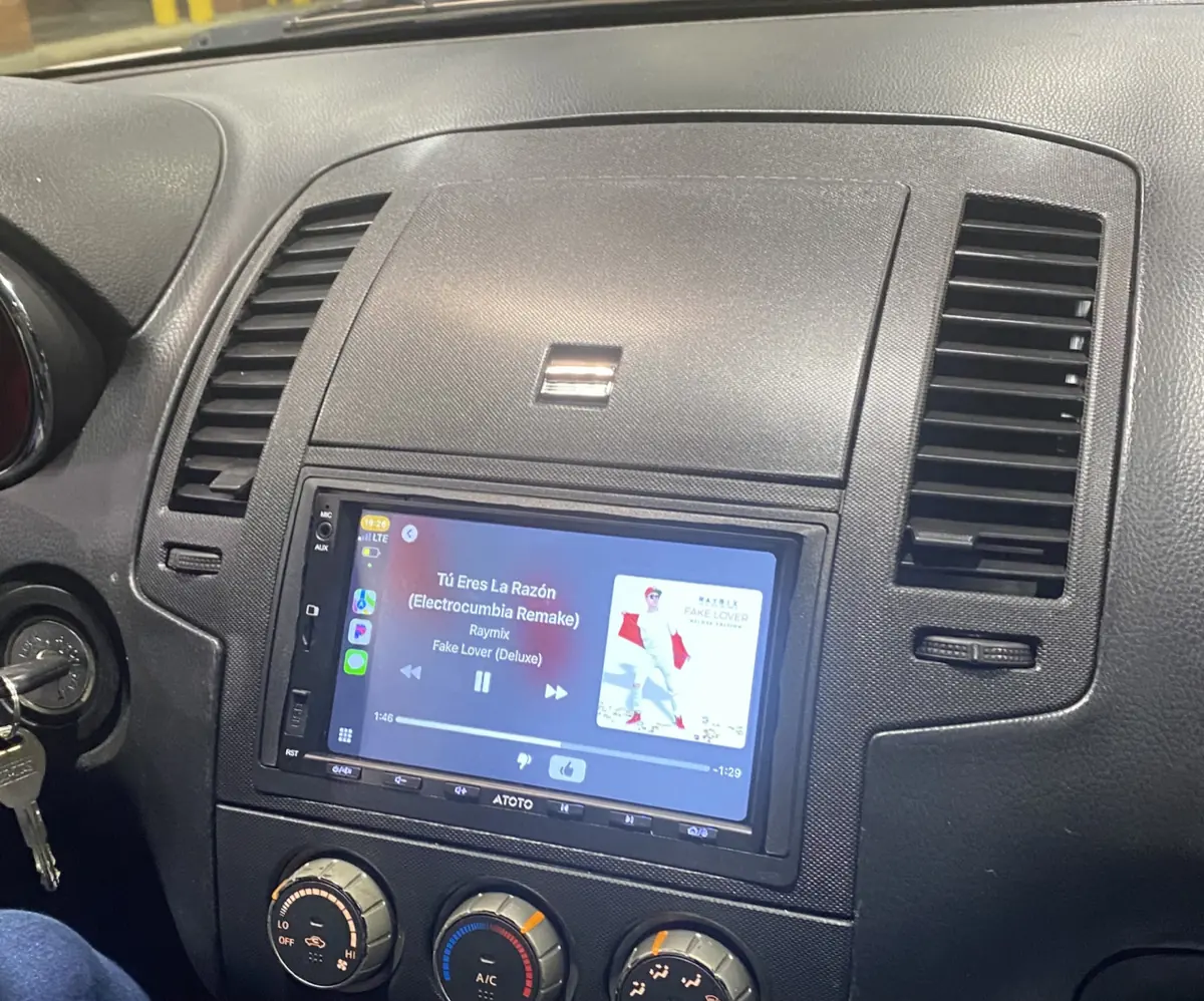 A car dashboard with a CarPlay screen playing music, with app icons down the left side